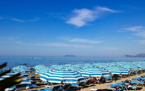a bunch of blue and white umbrellas on a beach at Hotel Aurora in Sperlonga