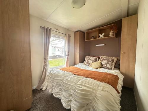 a bed in a small room with a window at Harwich - Caravan - Sleeps 10 - Garden - Pool in Harwich
