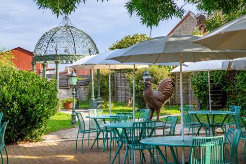 a statue of a camel standing next to tables with umbrellas at Hôtel De La Beursaudiere in Nitry