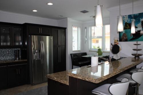 eine Küche mit schwarzen Schränken und einem Kühlschrank aus Edelstahl in der Unterkunft Luxury mansion with pool jacuzzi BBQ for ultimate scape in Tamiami