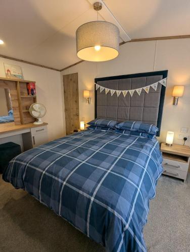 a bedroom with a bed with a blue plaid blanket at BEAUTIFULLY PRESENTED CARAVAN DOG FRIENDLY on AWARD WINNING SHOREFIELD COUNTRY PARK Entertainment passes and linen included in Milford on Sea