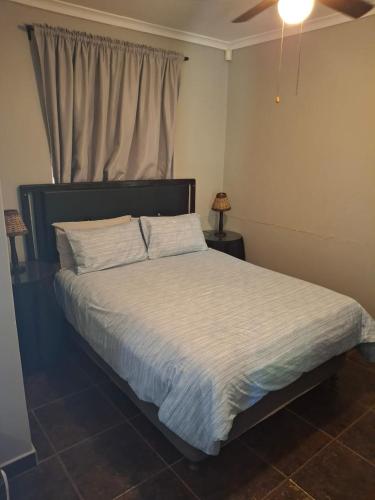 a bedroom with a bed with a white comforter at Timeless at Rusticana in Klapmuts