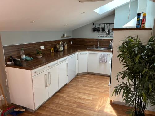 une cuisine avec des armoires blanches et un plancher en bois dans l'établissement La Sèvre, à Le Longeron