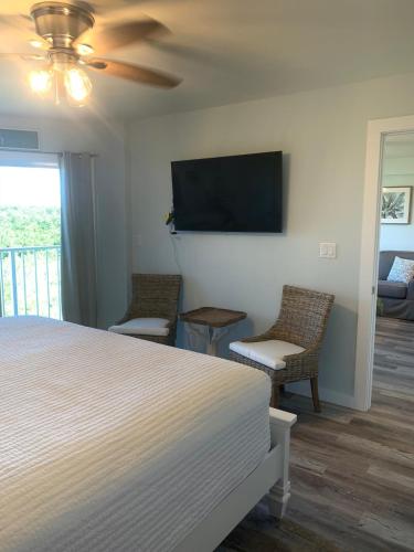 a bedroom with a bed and two chairs and a flat screen tv at Ocean Pointe Resorts - Serenity 2308 in Tavernier
