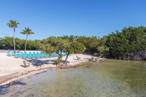 an empty beach with chairs and palm trees and water at Ocean Pointe Resorts - Serenity 2308 in Tavernier