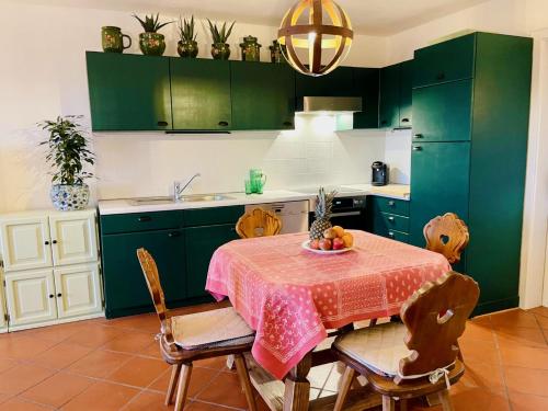 a kitchen with green cabinets and a table with fruit on it at Apartment in South Tyrol with a beautiful panoramic view in Verano