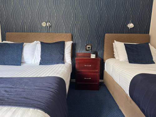 a hotel room with two beds and a night stand at Oaklands Hotel in Norwich