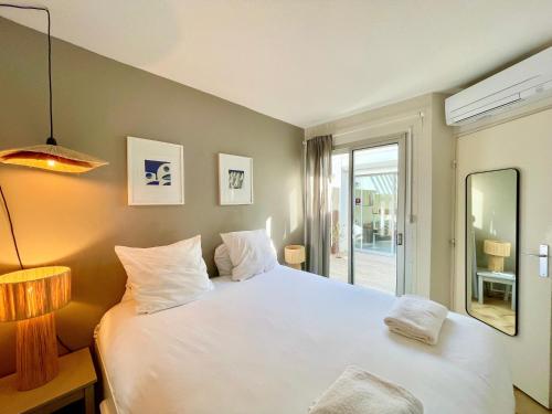 une chambre avec un grand lit blanc et un miroir dans l'établissement PGH N3 - Maison de Plage avec Parking Privé, à La Grande Motte