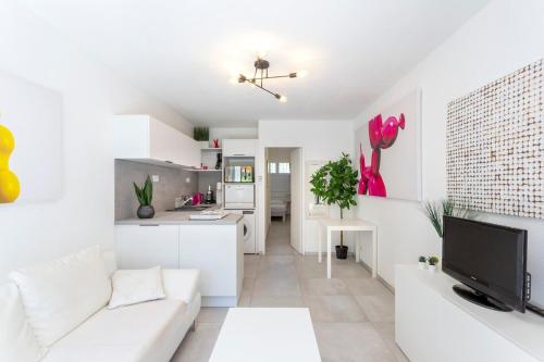 Il comprend un salon blanc avec un canapé blanc et une cuisine. dans l'établissement Sable et Mediterranée, à La Grande Motte