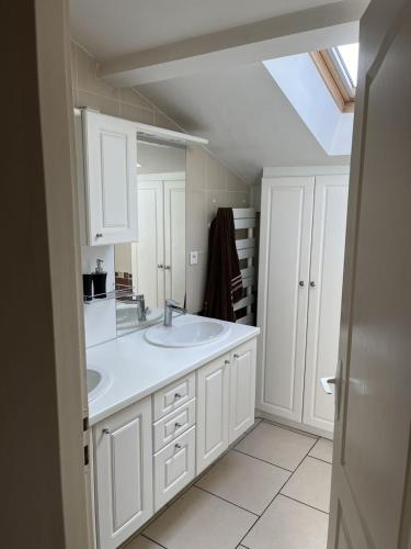 une salle de bain blanche avec un lavabo et un miroir dans l'établissement Auberge des Quatre Moulines, à Le Longeron