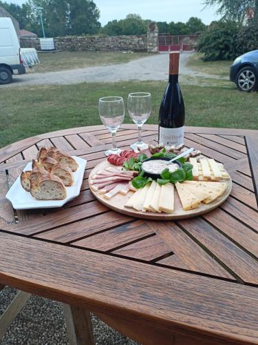 - une table avec une bouteille de vin, du fromage et du pain dans l'établissement Logis Dézamy chambre d'hôtes, à La Couture