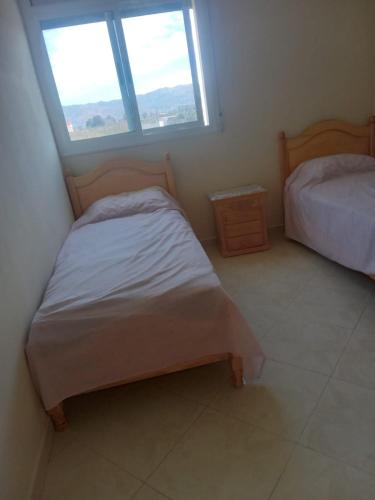 a small bedroom with two beds and a window at Appartement Souani - Al Hoceima in Al Hoceïma