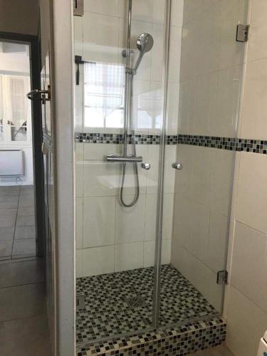 une douche avec une porte vitrée dans une salle de bain dans l'établissement Le Clos des Lilas, Gîtes de Charme, à Daglan