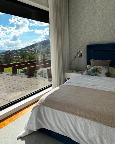 a bedroom with a bed and a large window at Moradia Vila Golfe in Amarante