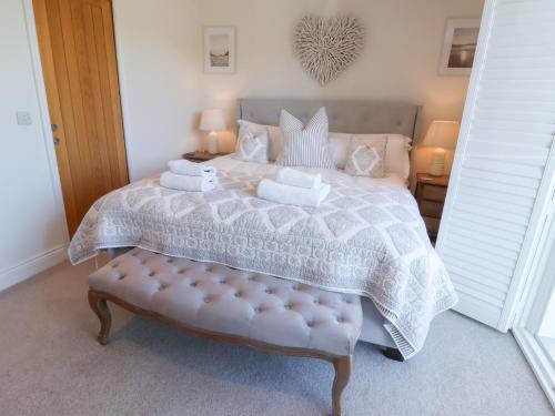 a bedroom with a large bed with a bench in it at Sundowners in Southwold