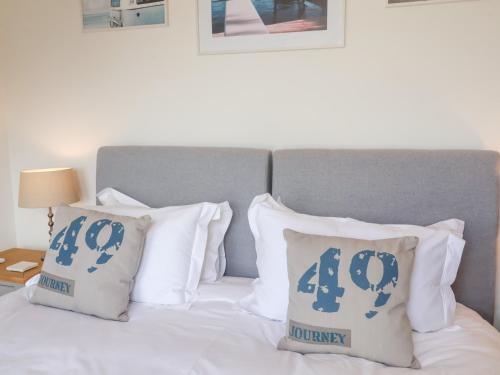 a bed with blue and white pillows on it at Sundowners in Southwold