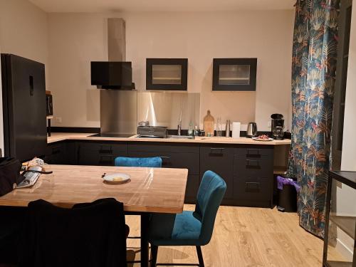 une cuisine avec une table en bois et des chaises bleues dans l'établissement Appartement rénové centre ville, à Quimper