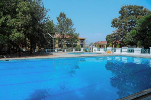 a large blue swimming pool with a building in the background at Central Jimma Hotel in Jīma