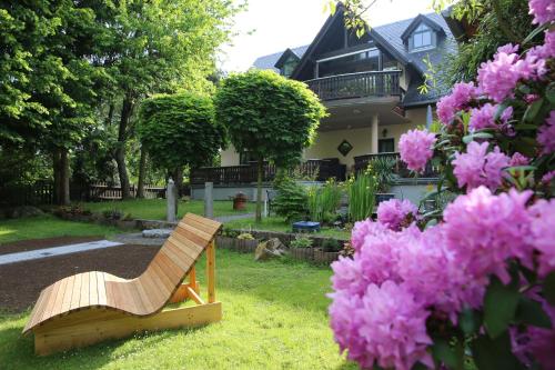 a wooden chair sitting in the grass next to pink flowers at Landhotel Villa Moritz garni in Oberahr