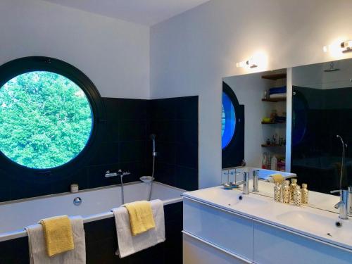 une salle de bain avec un lavabo et une grande fenêtre dans l'établissement Villa D'architecte dans un petit coin de paradis, à Cazats