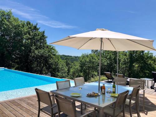 - une table avec un parasol à côté de la piscine dans l'établissement Villa D'architecte dans un petit coin de paradis, à Cazats
