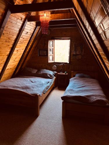 a bedroom with two beds in a wooden attic at Cabin Rujište in Padežina