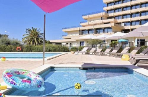 - une piscine avec un parasol et une piscine gonflable dans l'établissement Résidence LES CALANQUES route des sanguinaires- Piscine - Parking & Wifi Gratuit - Plage, à Ajaccio