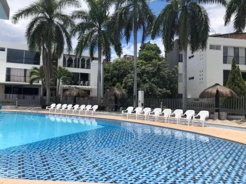 a swimming pool with white chairs and palm trees at Hermoso Apartasol!! cerca a Plaza Principal, Aire Acondicionado, Vista a la Piscina in Santa Fe de Antioquia