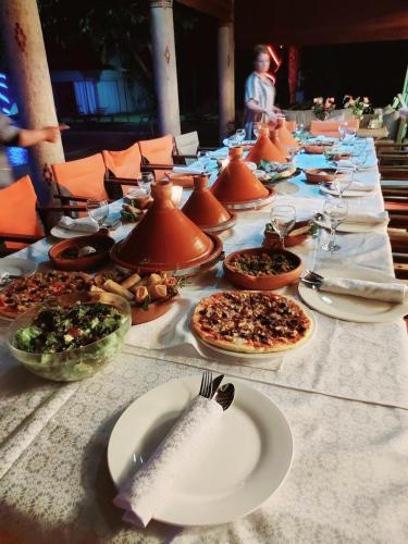 a long table with plates of food on it at Villa Rosa - Iconic Riad on 2 hectares of privacy in El Aggada