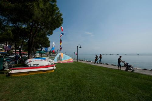 a group of boats sitting on the grass near the water at Hotel Villa Rosa in Sirmione