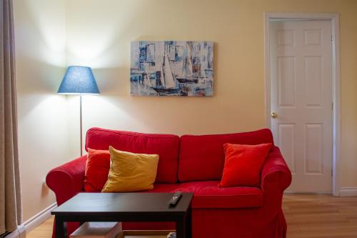 a red couch with yellow and red pillows in a living room at Calm, cozy, urban, family-friendly stay in Vancouver