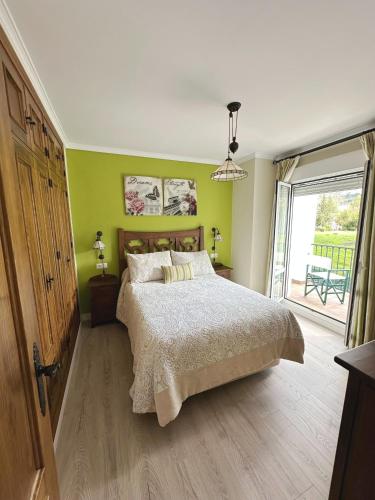 a bedroom with a bed with green walls and a window at El mirador de El Bosque in El Bosque