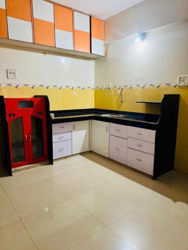 a large kitchen with orange and white walls and counters at Siddhi Row House -2 BHK Bungalow in Nashik