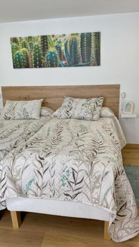 a bed with a comforter and pillows in a bedroom at Gallaecia Dúplex in Arzúa