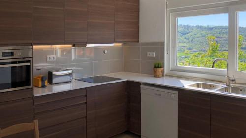 a kitchen with brown cabinets and a window and a sink at Spacious House with Private Pool Kitchen in Teixoso