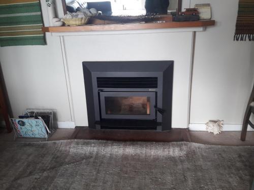a fireplace in a living room with a mantle at Ahu in Piha