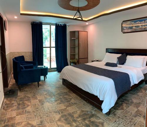 a bedroom with a large bed and a blue chair at Hotel Birmingham Palace Kalam by Khan Familia Travels in Kalām