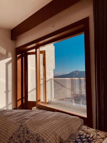 a bedroom with a large window with a view of the desert at Satyam Shivam Sundaram in Mukteswar