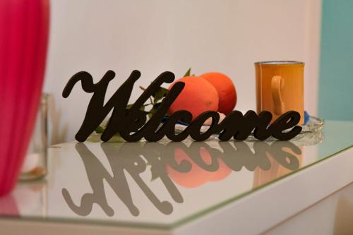 a welcome sign with two oranges and a candle on a shelf at Madre Terra Airport Apartment & Rooms in Terrasini