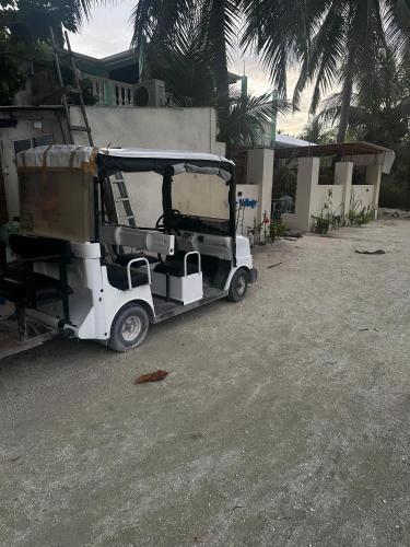 a small white golf cart parked in front of a house at Blue Village Maamigili in Maamigili
