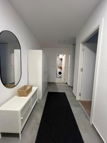 a white hallway with a mirror and a black rug at Sassy in Belgrade