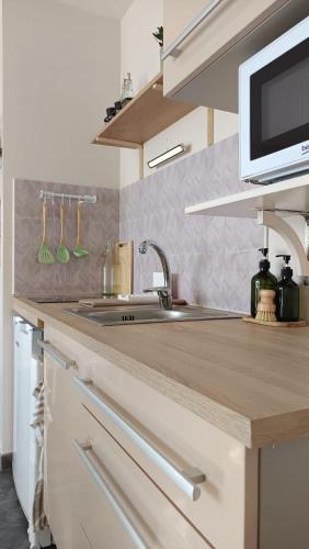 un comptoir de cuisine avec un évier et un micro-ondes dans l'établissement Appartement Lumineux hypercentre - Biscarrosse, à Biscarrosse