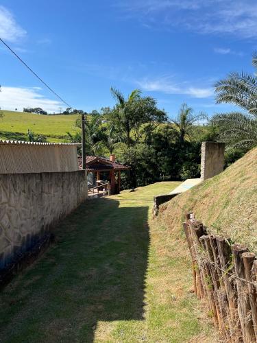 a grassy hill next to a house with a fence at Chácara Águas Claras in Monte Sião