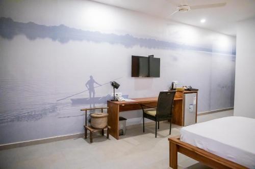 a bedroom with a desk and a tv on a wall at L'Hédone, hôtel de charme in Ouagadougou