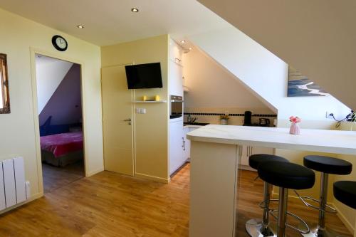 une cuisine avec un comptoir et des tabourets dans une pièce dans l'établissement Cozy apartment with exceptional sea view - CANCALE, à Cancale