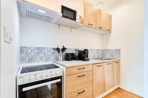une petite cuisine avec une cuisinière et un micro-ondes dans l'établissement Autumn, Centre-Ville Gare, Spacieux, Netflix, à Reims