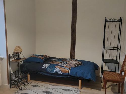 ein Schlafzimmer mit einem Bett mit einer blauen Bettdecke in der Unterkunft Maison avec jardin clos à Villabon - FR-1-586-55 in Villabon