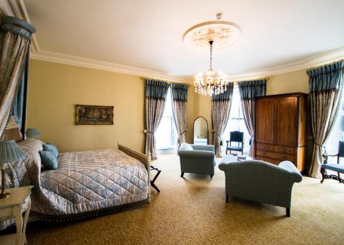 a bedroom with a bed and a chair and a chandelier at Crossbasket Castle, Hotel & Restaurant in High Blantyre