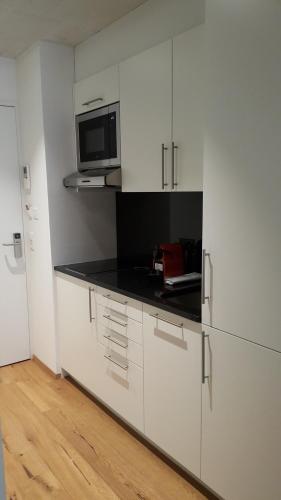 a white kitchen with a microwave and a refrigerator at Residence Appartements in Zürich