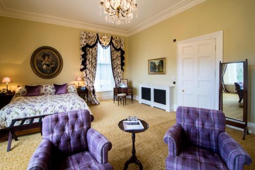 a bedroom with a bed and two purple chairs at Crossbasket Castle, Hotel & Restaurant in High Blantyre